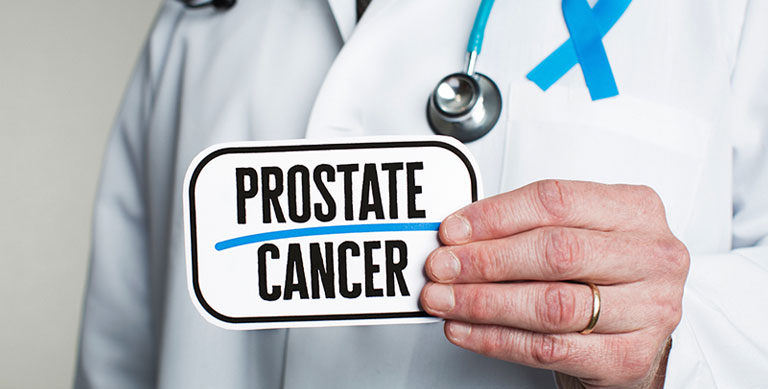 Doctor with stethoscope in white lab coat holding sign reading prostate cancer